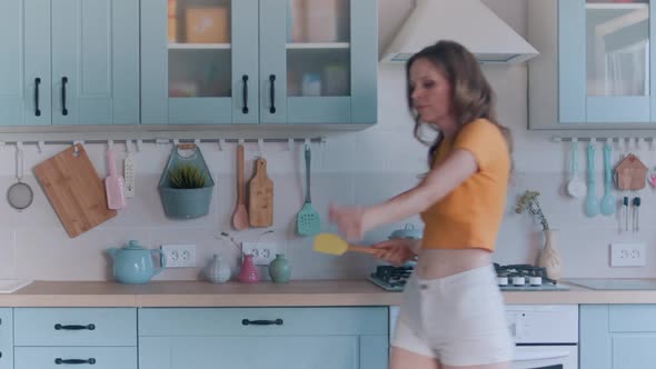 A Beautiful Woman in White Shorts is Relaxing at Home Dancing in the Kitchen