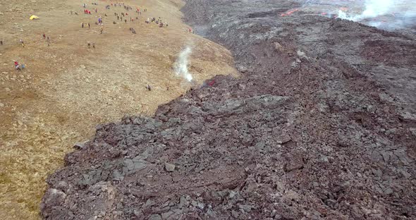 Drone shot of cooling lava with people close by watching the volcano. Fagradalsfjall in Reykjavík, I