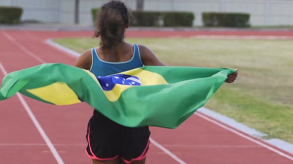 Young Biracial Winner of Sports Competition Running on Arena with Flag of Brazil