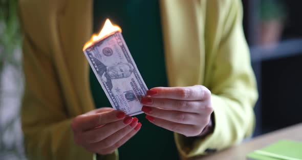 A Woman in a Jacket Burns Dollars Closeup