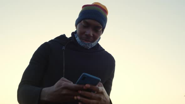 African American Man Out and About in the City Streets During the Day, Wearing a Face Mask Against