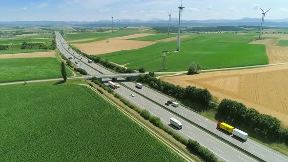 Aerial View of a Trucks and Cars on a Road Autobahn in Beautiful Countryside Field with Windmills