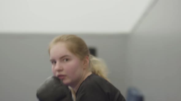 Portrait Young Blond Girl Panching on Camera in Boxing Gloves