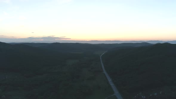 Aerial Drone View of Road Between Green Hills on Sunset