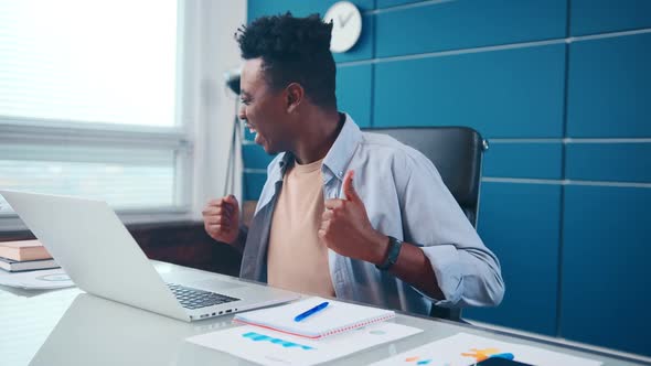 Young African American Man Rejoices at What He Saw in Laptop Laughs and Waves Hands