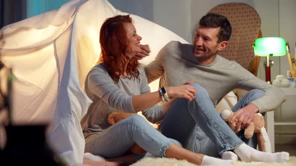 Wide Shot Happy Adult Couple Hugging Sitting at Tent in Living Room Talking in Slow Motion Smiling