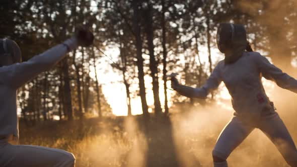 Two Sportsmen in Outfit and Masks Fencing in Forest in Slowmotion