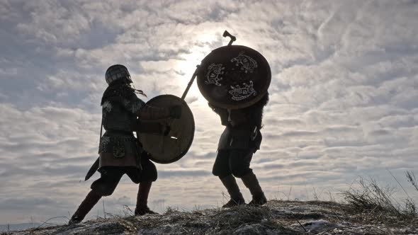 Two Warriors Viking Are Fighting with Axes and Shields on the Winter Meadow.