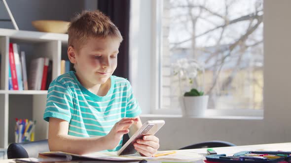 Boy is Doing  Homework at the Table. Cute Child is Learning at Home.