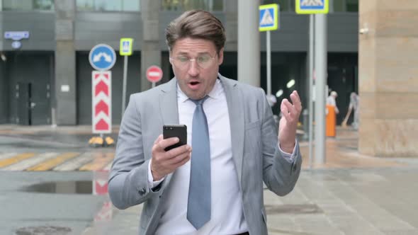 Businessman Having Loss on Phone while Walking on Street