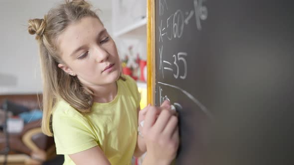 Portrait of Genius Caucasian Girl Solving Math Problem on Blackboard at School