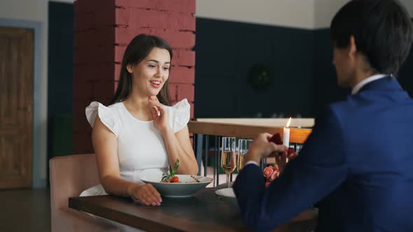 Loving Young Man Is Making Proposal To His Girlfriend in Restaurant, Girl Is Saying Yes