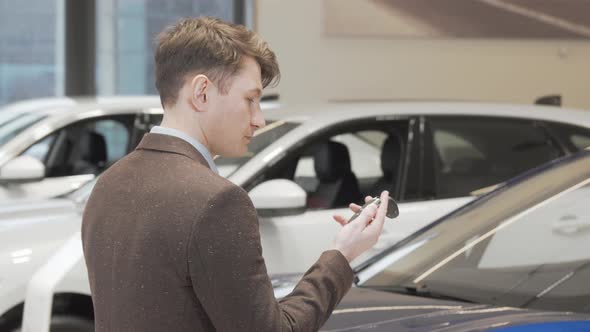 Cheerful Mature Man Smiling to the Camera Holding Car Keys at the Dealership