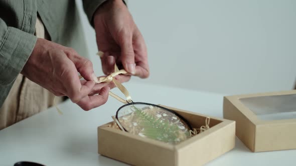 Woman Ties a Bow on a Handmade Christmas Tree Toy