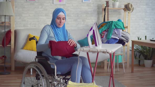 Beautiful Muslim Woman Disabled in a Wheelchairdoing Homework Ironing Clothes