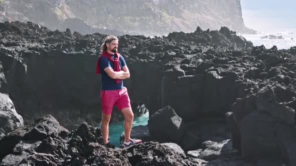 Man Wearing Red Shorts Standing on a Volcanic Rock