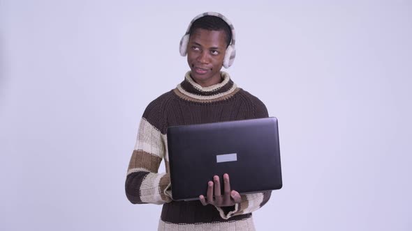 Young Happy African Man Thinking While Using Laptop Ready for Winter