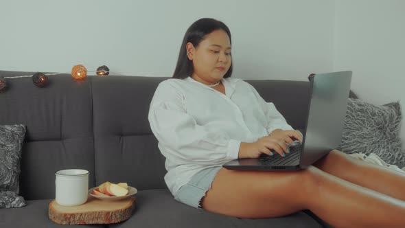 Asian Plus Size Woman Working Online with Laptop at Home
