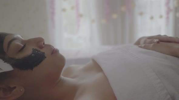 Young beautiful woman makes charcoal spa therapy