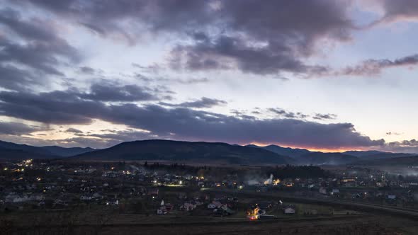 Small Town Turns on Lights Under Dark Evening Sky at Sunset