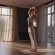 A Young Woman in White Sportswear is Stretching with a Large Hall with Large Windows in a Slowmotion - VideoHive Item for Sale