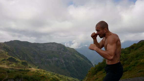 an Unshaven Man with a Bare Muscular Torso is Boxing in the Mountains