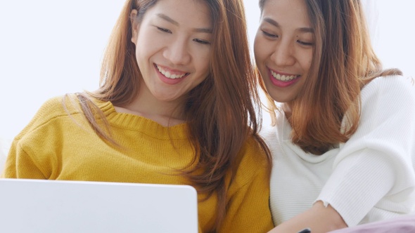 Young Asian lesbian couple using laptop on bedroom at home.