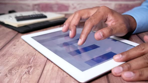 Close Up of Businessman's Hand Analyzing Bar Chart on Digital Tablet 