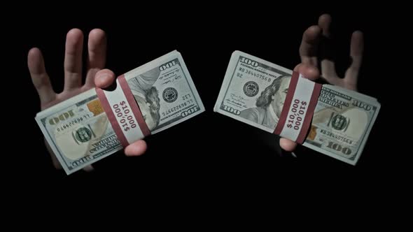 Two Stacks of 10000 American Dollars Bundles in Male Hands on Black Background