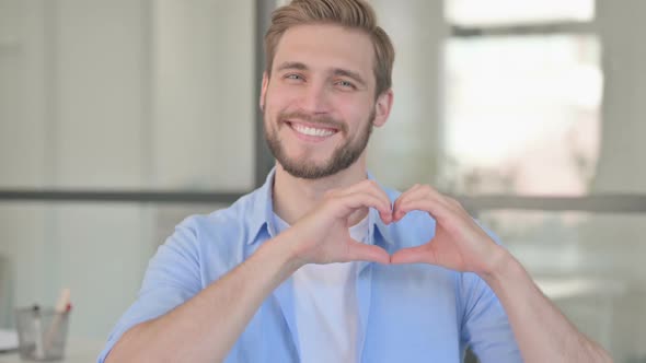 Portrait of Young Creative Man Showing Heart Sign By Hand