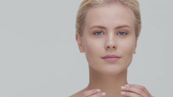 Studio portrait of young, beautiful and natural blond woman applying skin care cream. F