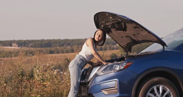 Young Woman Looking at Open Hood of Broken Car, Then Trying To Catch Vehicle for Help