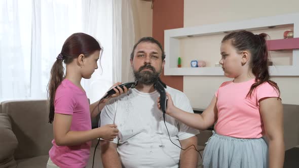 Two little girls trim their father's beard with electric clippers during quarantine. Adaptation