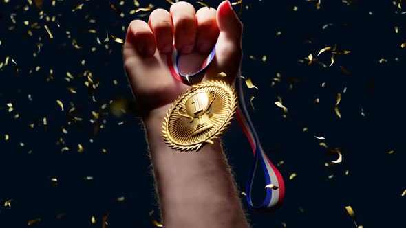 Rising hand holding a shiny gold medal. Top winner with first prize. Victory.