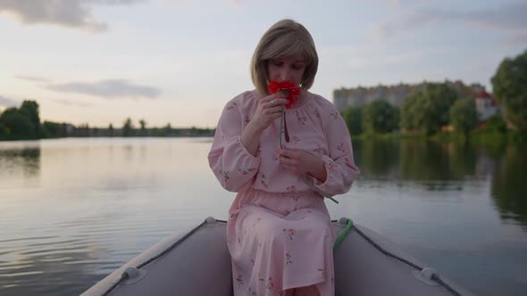 Romantic Trans Woman Smelling Red Flower Sitting in Boat Dreaming