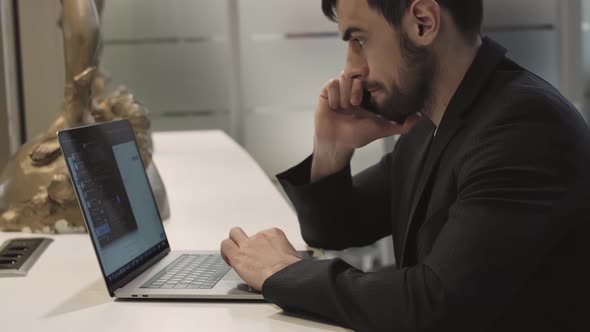 Young Focused Handsome Male Businessman Working on a Laptop