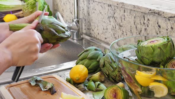 Woman Cleaning Heart of Artichokes with Spoon