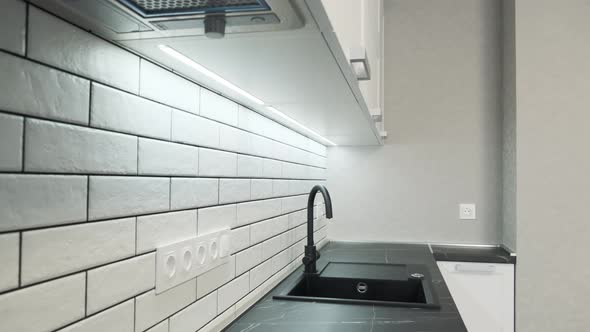 Kitchen Sink and Faucet. Simple Well Designed Modern White Wooden Kitchen Interior. Ceramic Tiles on