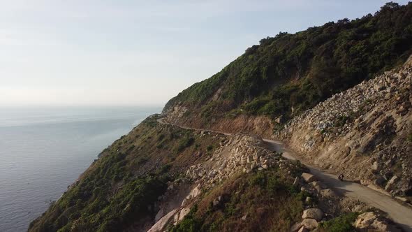 Aerial View of Motorist Driving Motorbike on Dangerous Coastal Cliffside Road