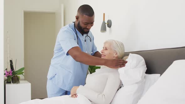 Video of happy african american male doctor supporting caucasian senior woman