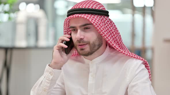 Cheerful Arab Businessman Talking on Smartphone in Office