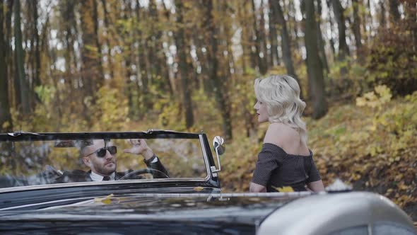 Lady and Man Looking on Each Other at Cabriolet Under Falling Autumn Leaves
