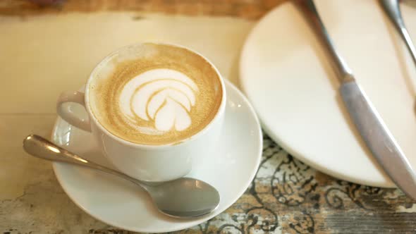 a Cup of Late Coffee with Flower Shape Design on Top at Cafe