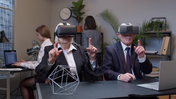 Elderly Old Man Boss with Woman Colleague Wearing Virtual Reality Glasses Tries 3D App for VR Helmet