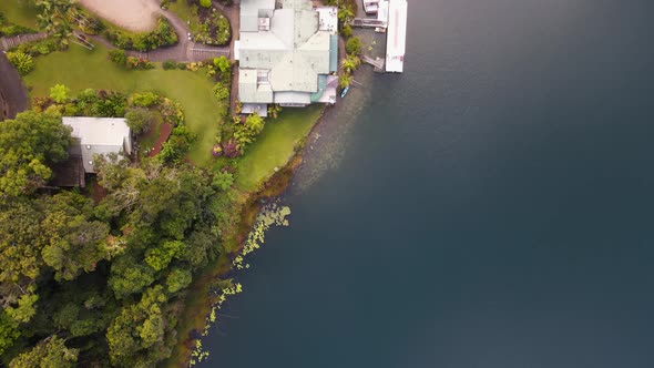 Moving drone video looking down on a lush park area next to a volcanic crater lake with boats docked