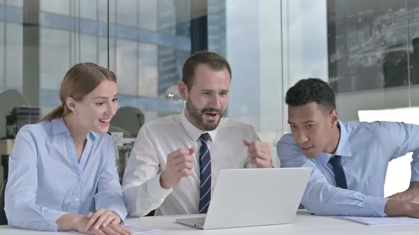 Business People Celebrating Success and Using Laptop on Office Table 