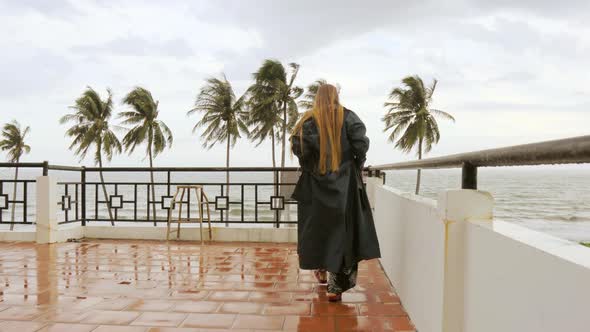 A girl on rooftop walking up to the ocean view with palm trees