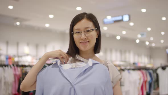 Happy Chinese Girl Posing with Smart Blouse in Clothing Store