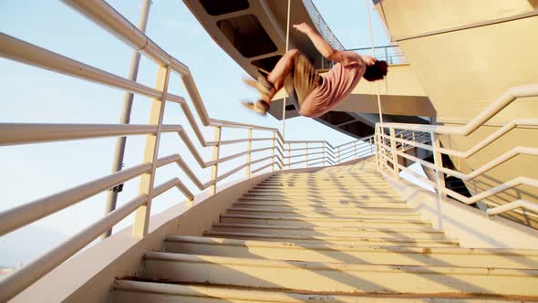 a Man Flips Backwards on the Stairs and Walks Up the Stairs in the Industrial Landscape