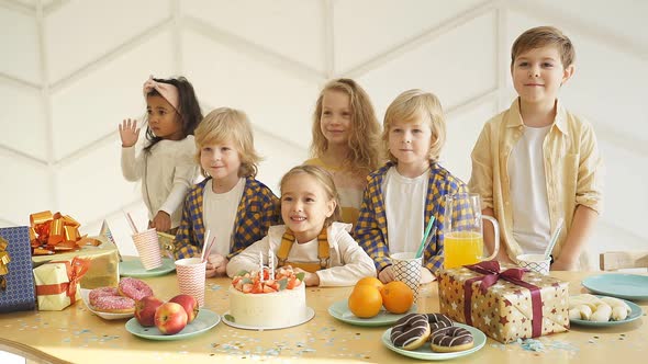 Children Gathered at a Festive Table Around the Birthday Girl